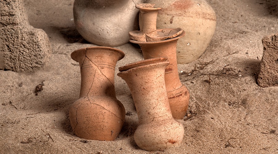 Yellow-orange urns resting on sand in the Tophet of Tharros.



