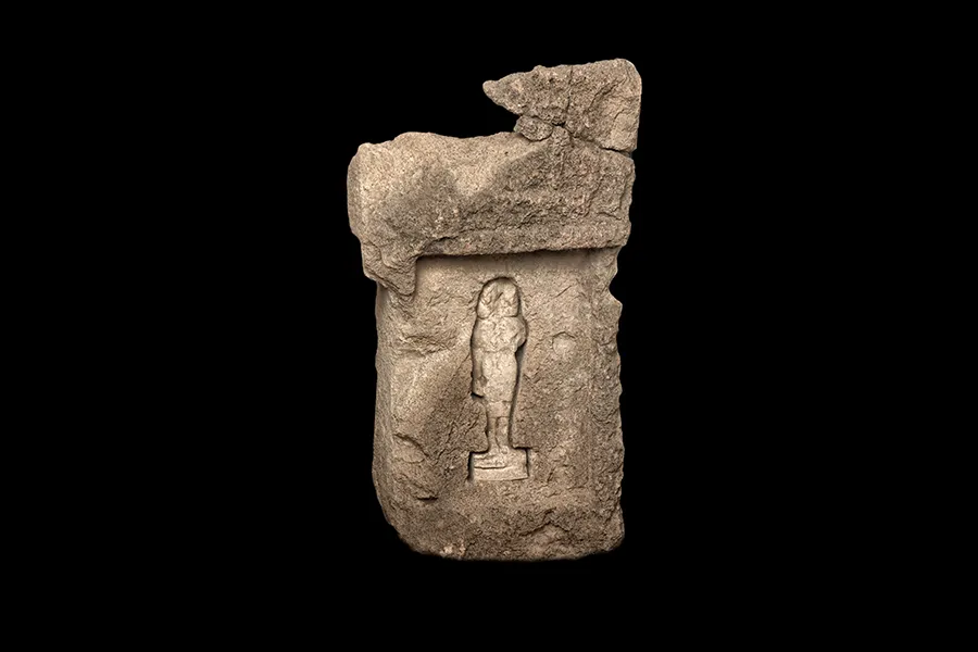 A sandstone stele from the Tharros tophet with a human statuette in white clay.